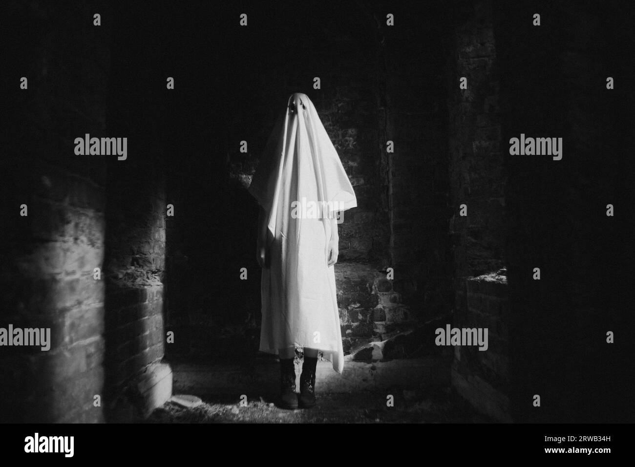La photo noir-blanc capture un fantôme debout dans un bâtiment abandonné la nuit. Mystère et horreur. L'image étrange rappelle Halloween et Banque D'Images
