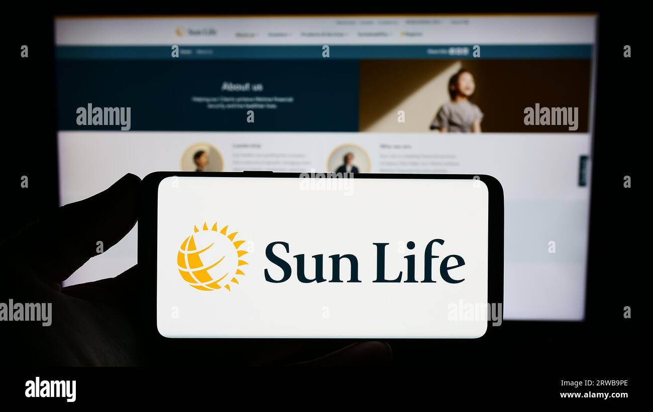 Personne détenant un téléphone intelligent avec le logo de la société canadienne financière Sun Life Inc. À l'écran devant le site Web. Concentrez-vous sur l'affichage du téléphone. Banque D'Images
