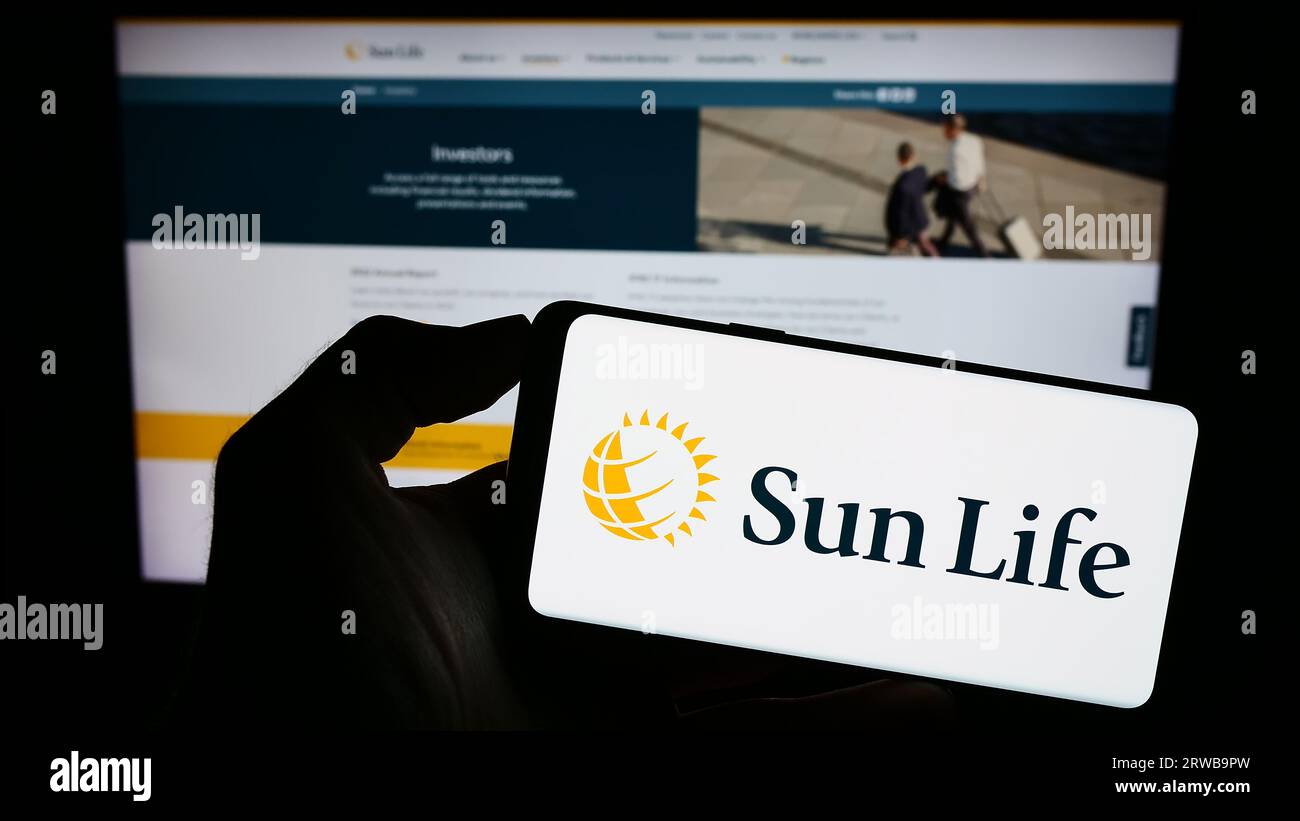 Personne détenant un téléphone cellulaire avec le logo de la société canadienne financière Sun Life Inc. À l'écran devant la page Web de l'entreprise. Concentrez-vous sur l'affichage du téléphone. Banque D'Images