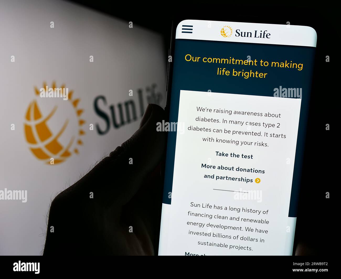 Personne détenant un téléphone cellulaire avec le site Web de la société canadienne financière Sun Life Inc. À l'écran devant le logo. Concentrez-vous sur le centre de l'écran du téléphone. Banque D'Images