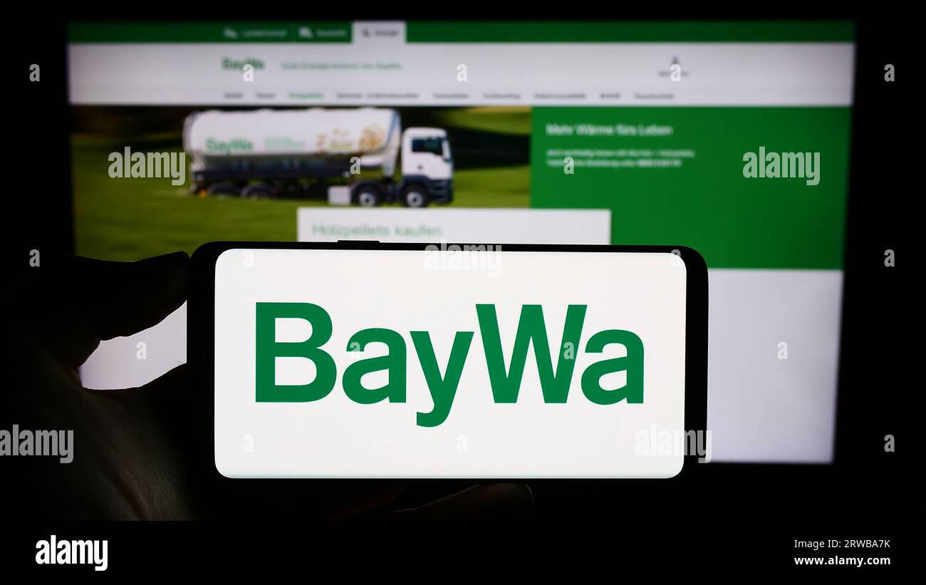 Personne tenant le téléphone portable avec le logo de la société agro-alimentaire allemande BayWa AG sur l'écran en face de la page Web de l'entreprise. Concentrez-vous sur l'affichage du téléphone. Banque D'Images