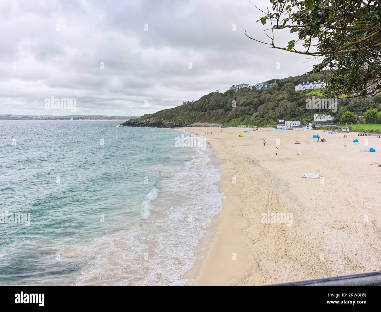 Les vacanciers et les vacanciers d'une journée sur la plage de sable de Porthminster à St Ives, Cornouailles, tandis que la marée de l'océan Atlantique est dehors par une journée nuageuse. Banque D'Images