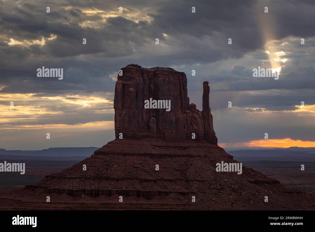 Formation rocheuse située sur un vaste terrain à Monument Valley sous le ciel du coucher du soleil plein de nuages en Amérique Banque D'Images