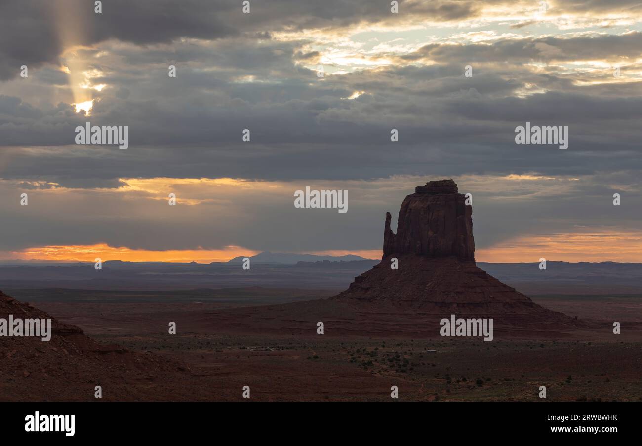 Formation rocheuse située sur un vaste terrain à Monument Valley sous le ciel du coucher du soleil plein de nuages en Amérique Banque D'Images