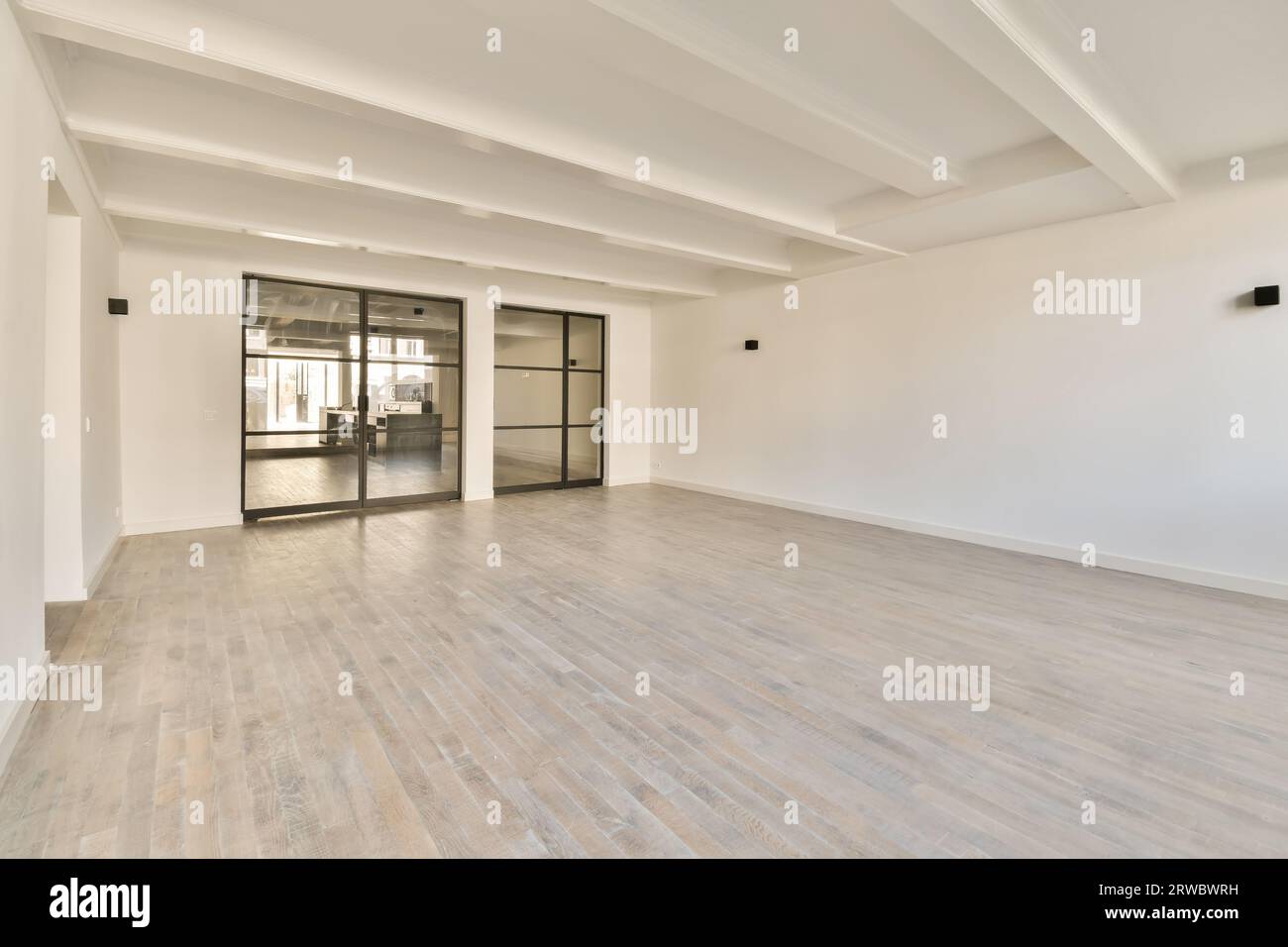 Intérieur de chambre vide spacieuse avec de grandes portes vitrées et des murs blancs avec sol stratifié dans un appartement moderne Banque D'Images