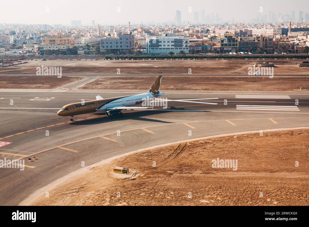 Un Airbus A321 de Gulf Air au sol à l'aéroport international de Bahreïn, Bahreïn, avec Muharraq et la ville de Manama photographiés derrière Banque D'Images