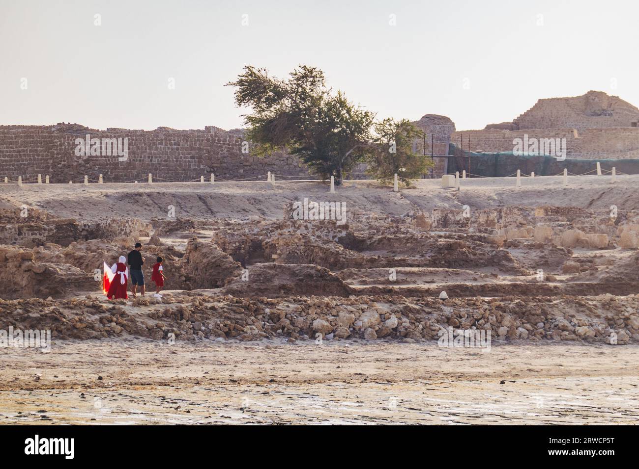 Une famille portant un drapeau bahreïnite explore le fort de Bahreïn, Al Qalah, Bahreïn Banque D'Images