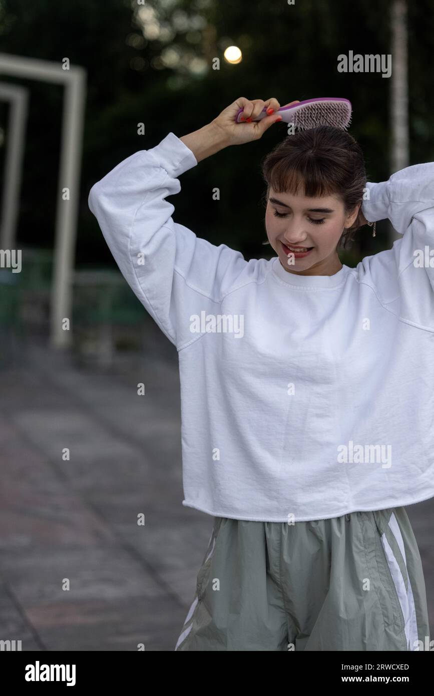 Jolie fille peigne ses cheveux dans la rue. Peigne. Banque D'Images