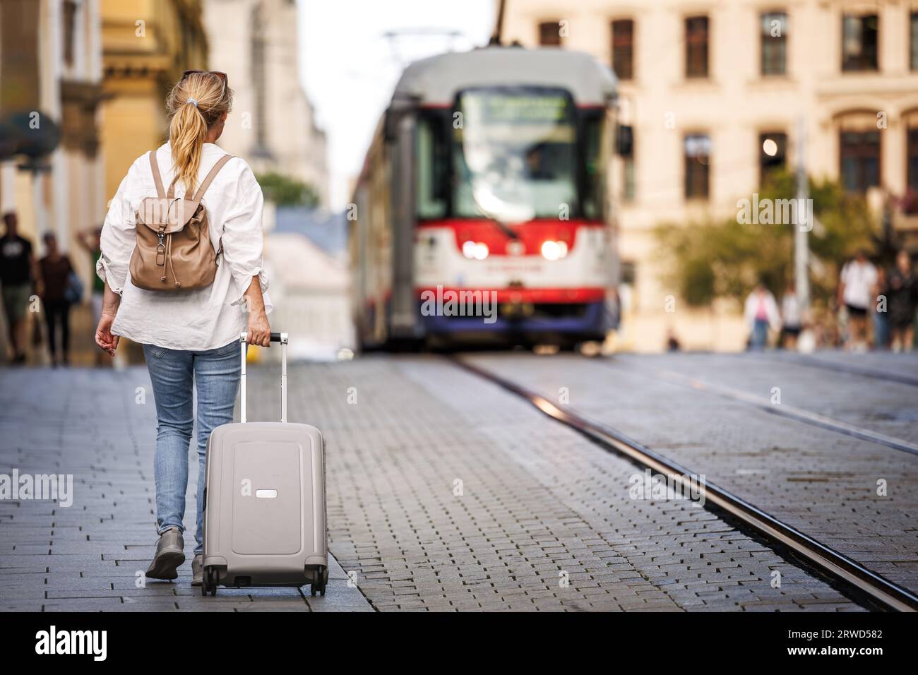 Femme voyageur avec valise et sac à dos marchant dans la rue. Voyage et vacances dans la ville européenne Olomouc, République tchèque Banque D'Images