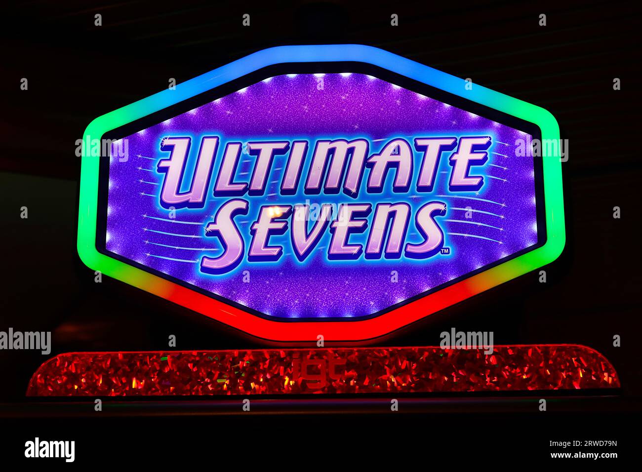 Graphiques colorés sur un panneau d'en-tête éclairé monté sur une machine à sous Arcade dans un casino de bateau de croisière pour attirer les loisirs de jeu. Banque D'Images