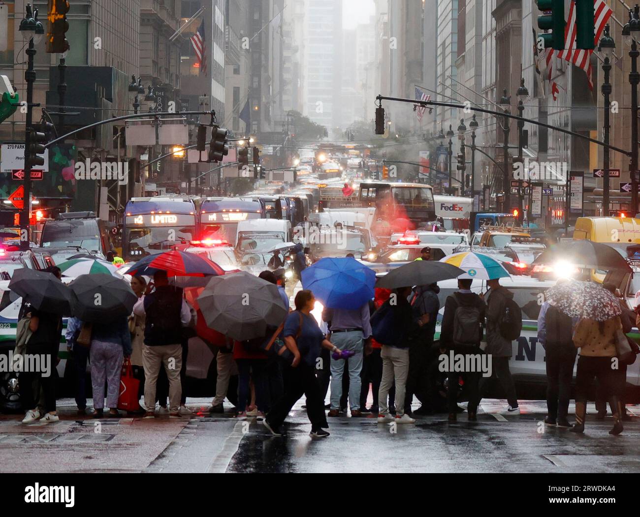 New York, États-Unis. 18 septembre 2023. Les piétons se tiennent debout sur Madison Avenue sous la pluie tenant des parapluies alors que la circulation est arrêtée pour les dignitaires se déplaçant dans la 49e rue alors que la 78e session de l'Assemblée générale des Nations Unies débat général commence au siège des Nations Unies le lundi 18 septembre 2023 à New York. Photo de John Angelillo/UPI crédit : UPI/Alamy Live News Banque D'Images