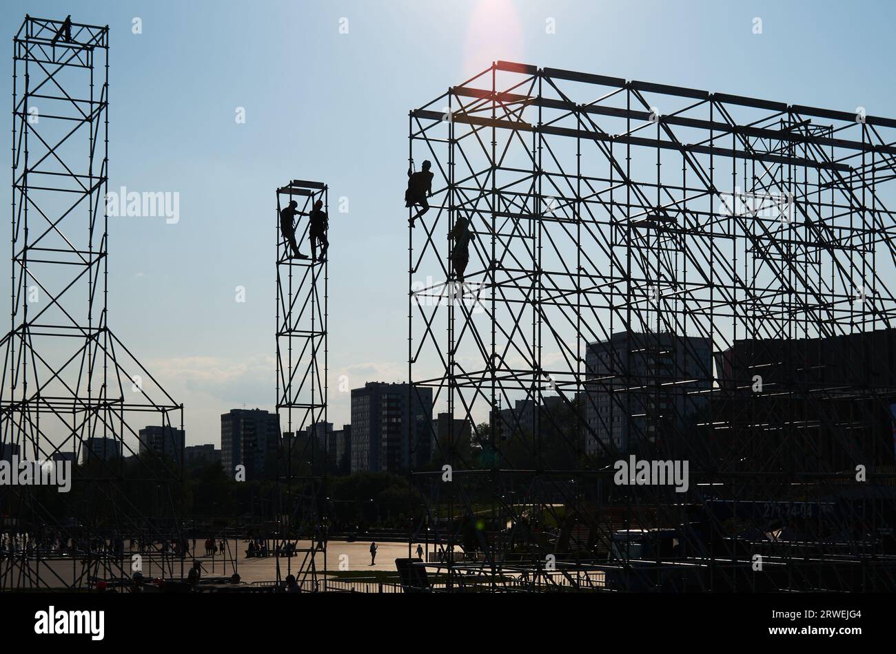 Silhouettes d'assembleurs de grande hauteur sur une ferme métallique sur le fond d'un ciel bleu et de la ville Banque D'Images