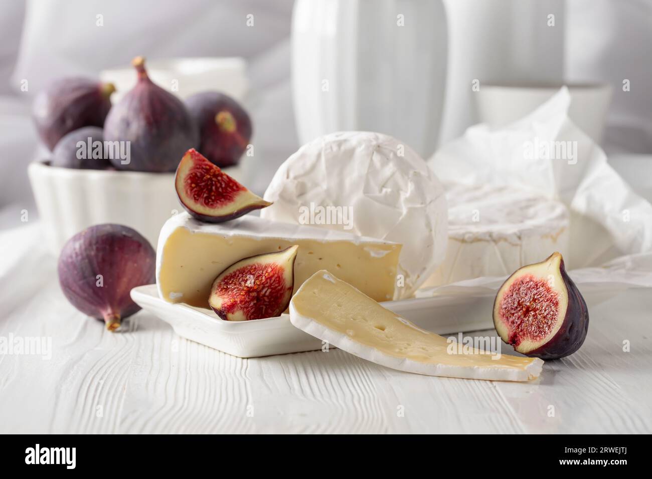 Fromage camembert avec des figues sur une table en bois blanc. Banque D'Images