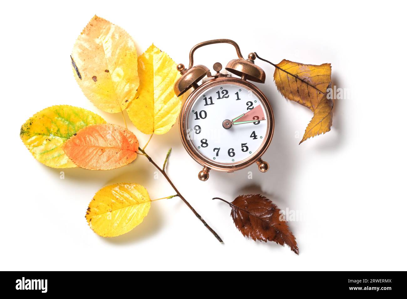 Retomber en automne après l'heure d'été en été sur un réveil vintage et quelques feuilles colorées sur un fond blanc, pose plate, espace de copie, Banque D'Images