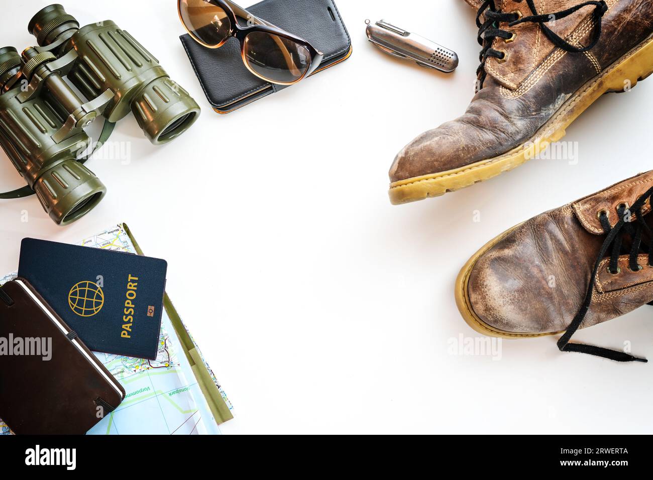 Bottes de trekking, jumelles, passeport et autres accessoires pour les vacances de randonnée, plat sur un fond clair, espace de copie, mise au point sélectionnée Banque D'Images