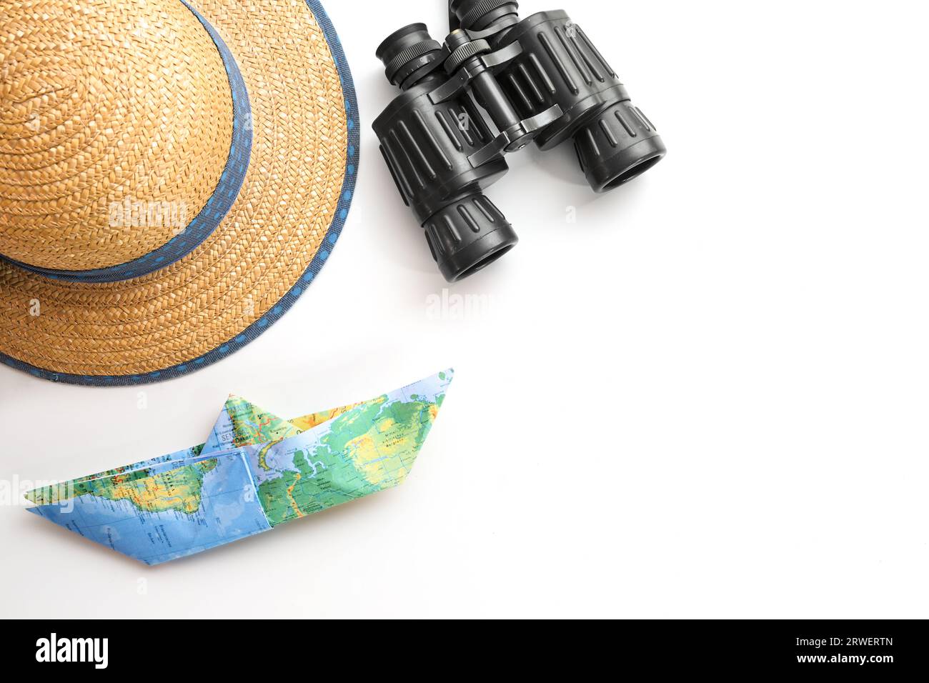 Chapeau de paille, jumelles et un bateau en papier plié à partir d'une carte sur fond blanc, concept pour croisière ou vacances sur la mer, espace de copie, focus sélectionné Banque D'Images