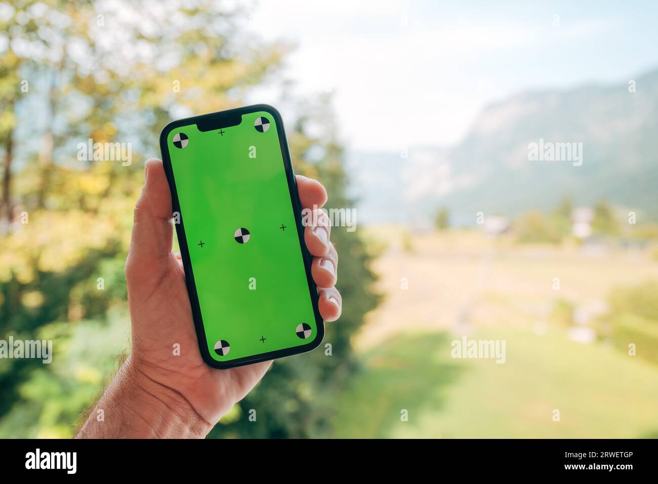 Main masculine tenant le téléphone intelligent avec maquette écran vert, mise au point sélective Banque D'Images