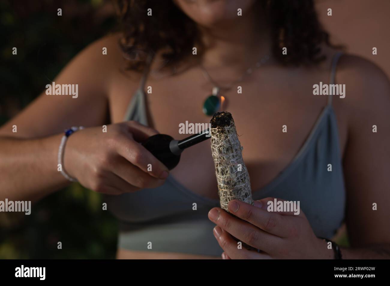 Portrait rapproché de la main d'une jeune femme allumant un bâton de maculage avec un briquet Banque D'Images