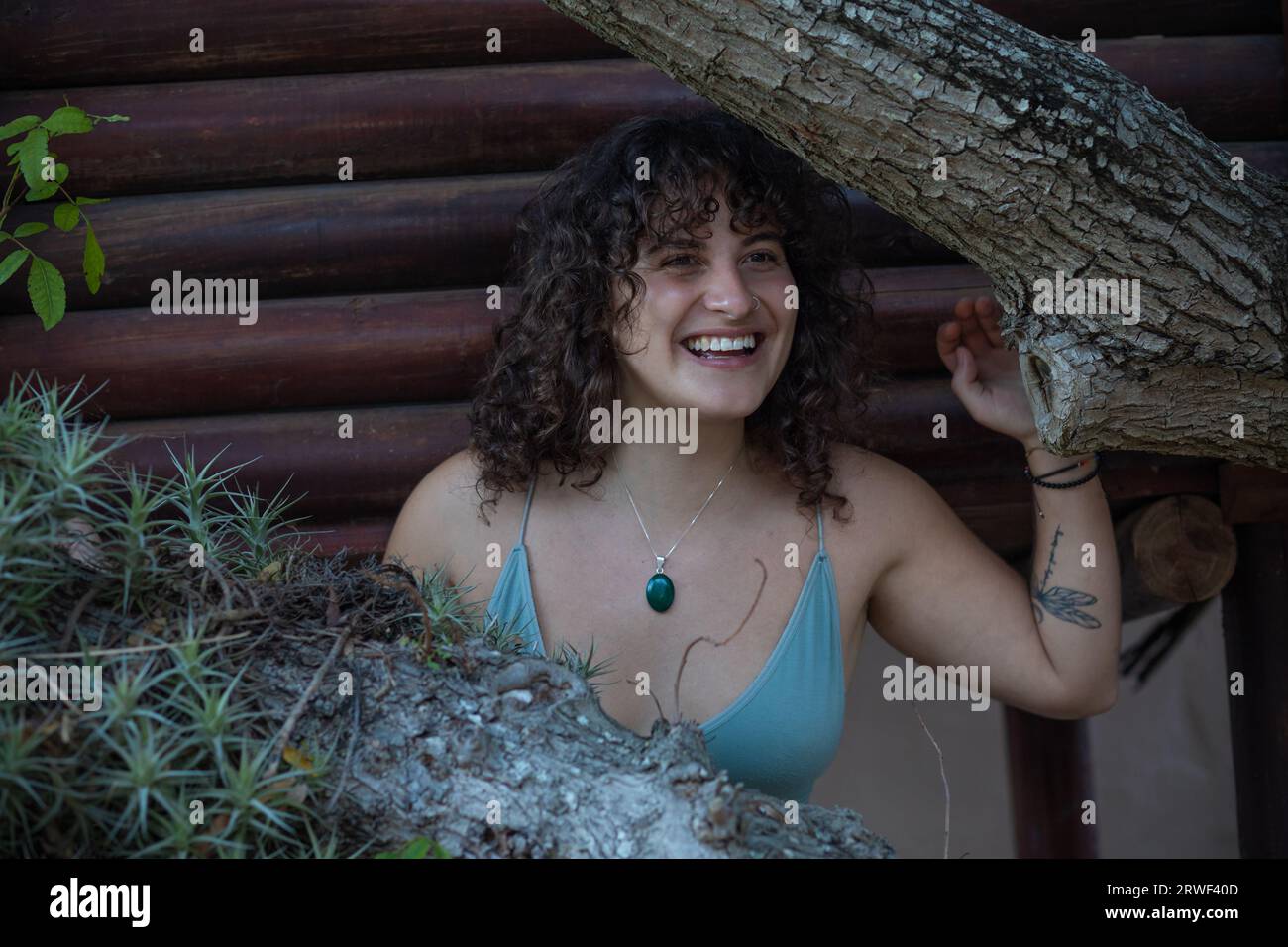 Au milieu des branches d'arbres, une jeune femme sourit joyeusement Banque D'Images