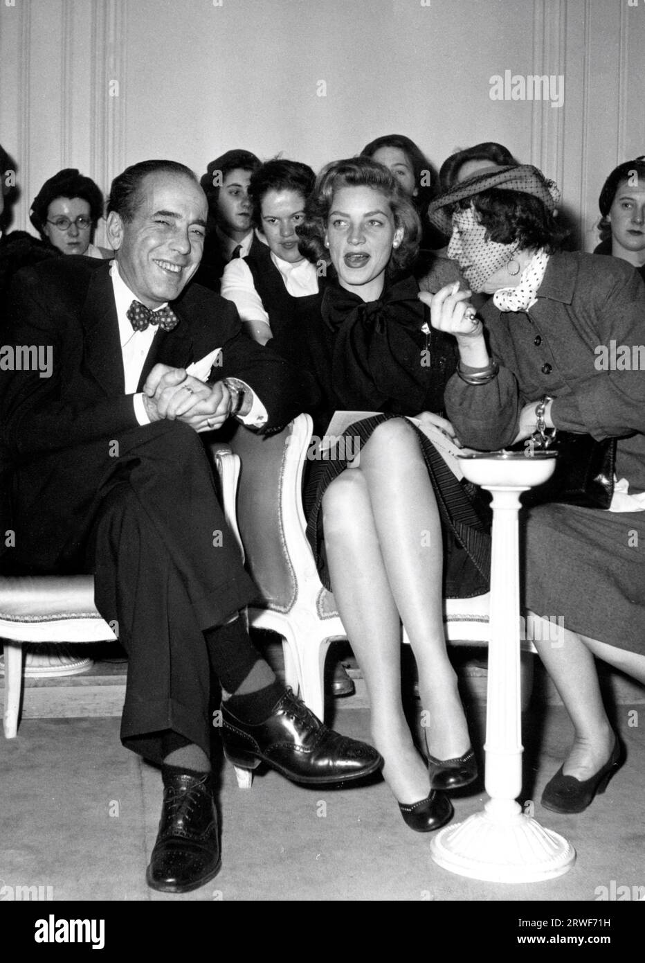HUMPHREY BOGART et son épouse LAUREN BACALL avec MARIE-LOUISE BOUSQUET, journaliste de mode française et rédactrice en chef parisienne du magazine Harper's Bazaar, lors de la présentation de la dernière collection de Christian Dior à la Maison de mode Dior à Paris le 22 mars 1951 Banque D'Images