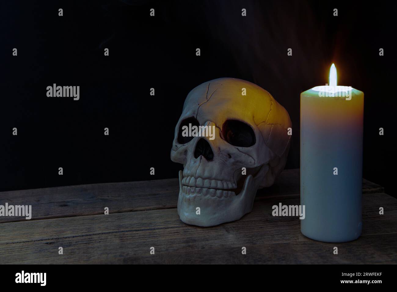Scull éclairé par une bougie sur une vieille table Banque D'Images