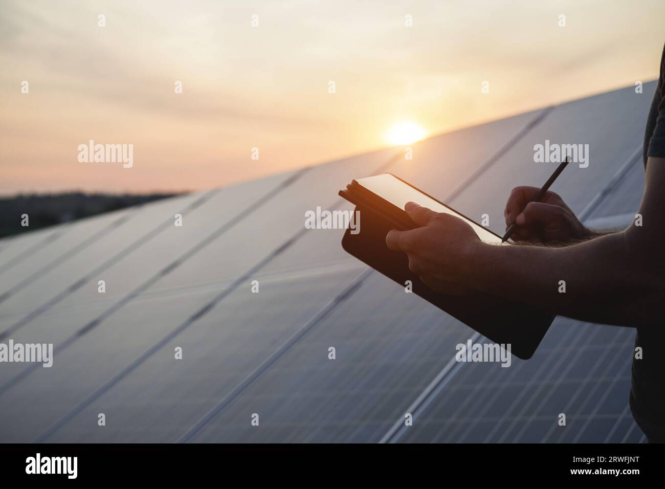 Ingénieur travaillant à l'usine de panneaux solaires en plein air - Photovoltaïque, énergie verte renouvelable et concept environnemental - Focus main gauche Banque D'Images