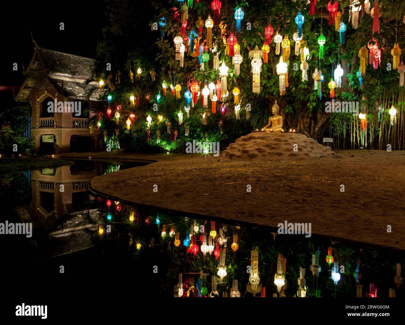 Lanternes colorées au-dessus de la statue de Bouddha. Décorations du festival Loy Krathong et une petite statue de Bouddha près de la rivière. Banque D'Images