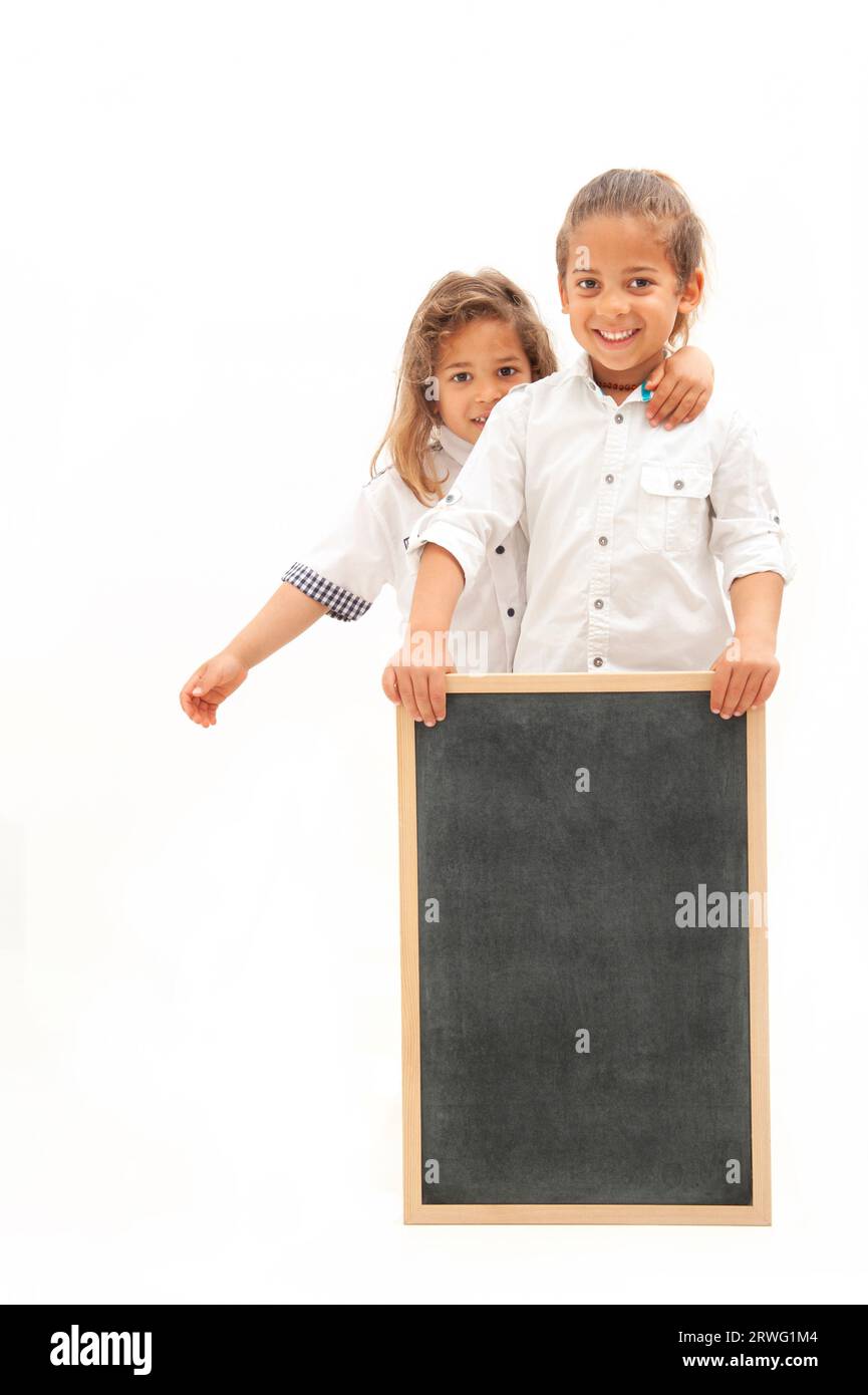 Inglese : deux enfants multiethniques aux cheveux longs tiennent un tableau blanc dans leurs mains, sur fond blanc Banque D'Images