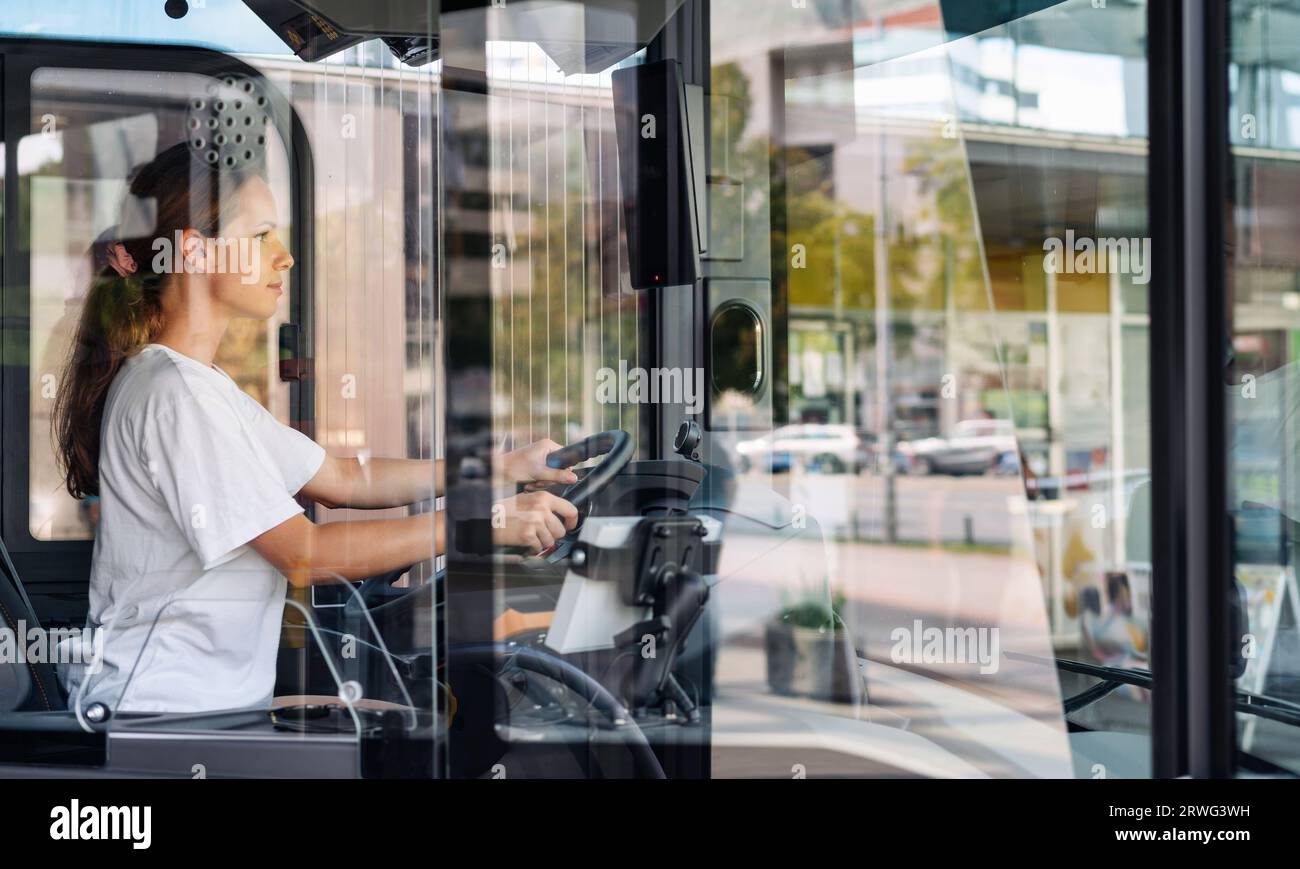 Photo d'une femme conductrice d'autobus à travers le verre de la cabine du conducteur. Banque D'Images
