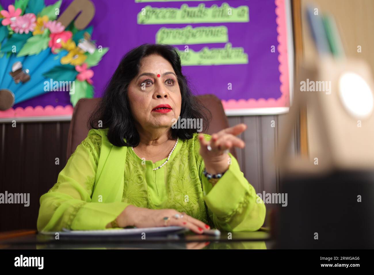 Directrice d'école assise dans son bureau avec agressivité, fuyant avec colère, expression furieuse. Banque D'Images