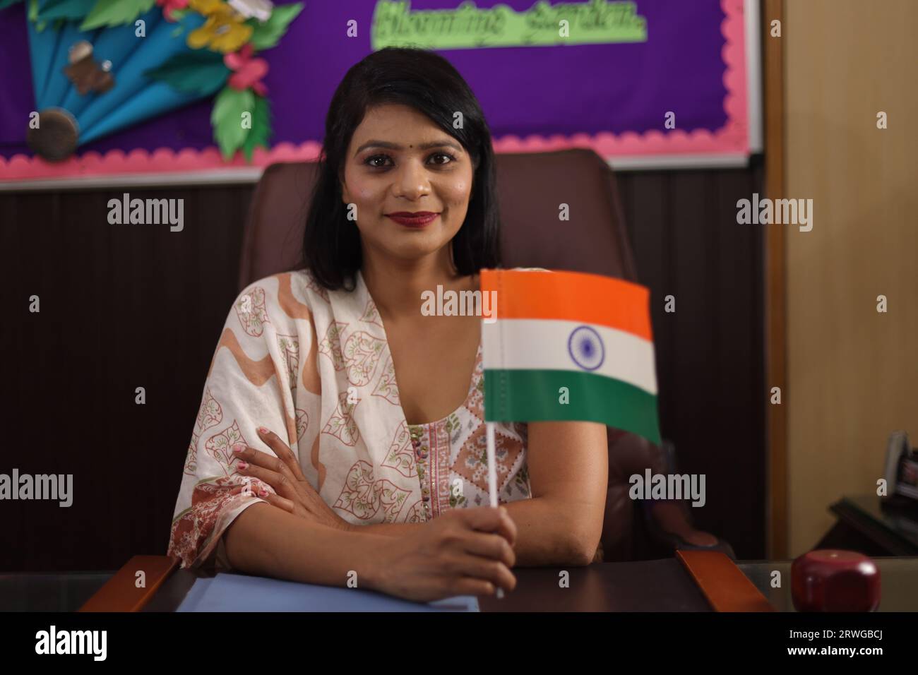Fière directrice d'école présentant le drapeau indien assis en toute confiance dans son bureau. regarder dans la caméra Banque D'Images