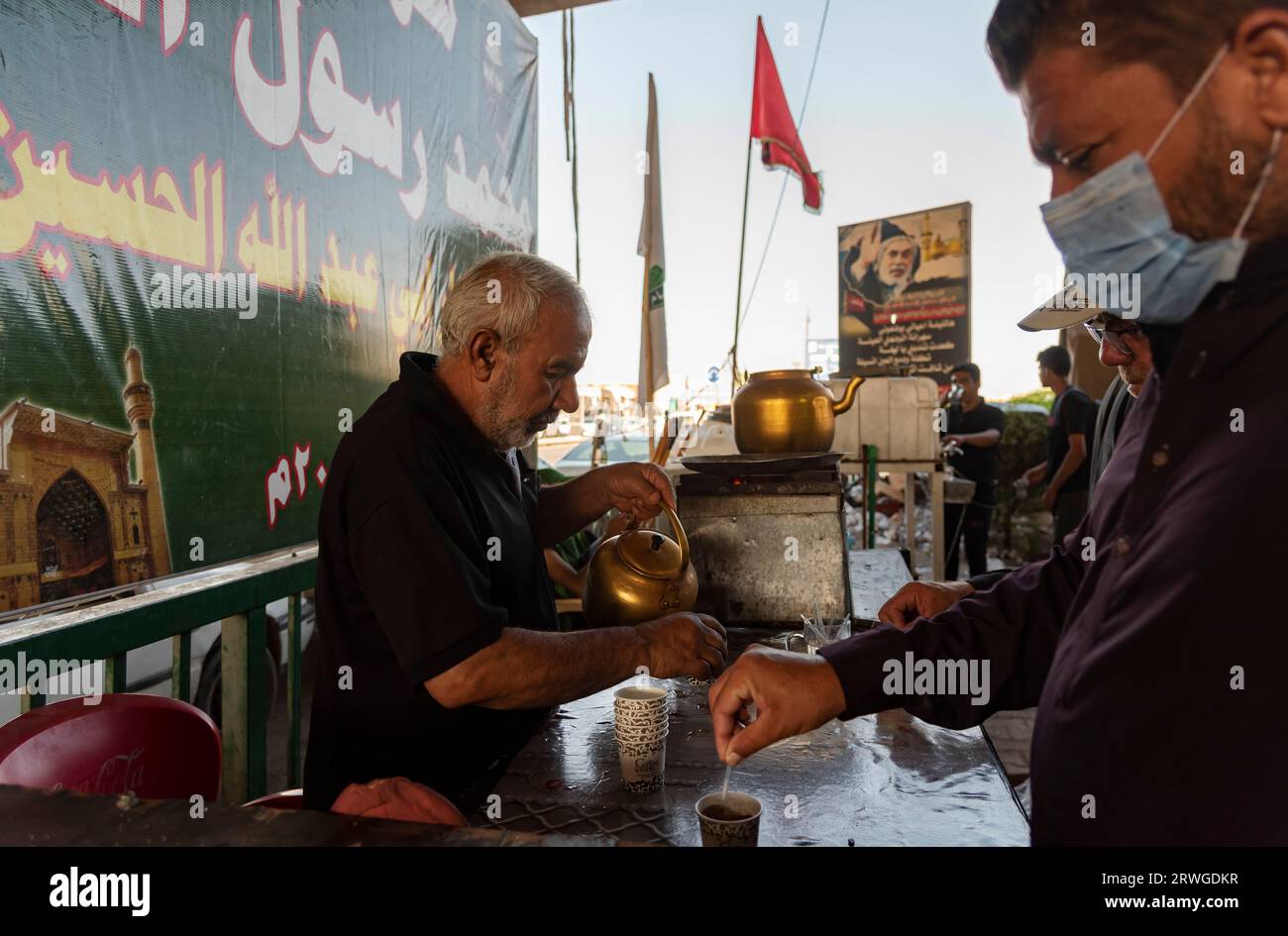 Un irakien distribue du thé parmi les pèlerins musulmans chiites marchant de Najaf vers la ville sanctuaire de Karbala. Chaque année, des millions de musulmans chiites et certains d'autres confessions entreprennent un pèlerinage de 20 jours à pied depuis diverses villes d'Irak et d'Iran jusqu'à la ville sainte de Karbala. Ce pèlerinage est en souvenir de l'Imam Hussein, le petit-fils du Prophète Muhammad, mort dans une bataille en 680 AD. Le 40e jour de deuil de Hussein, connu sous le nom d'Arbaeen, les pèlerins convergent à Karbala pour rendre hommage à son sanctuaire. Sur le chemin, les bénévoles fournissent de la nourriture, de l'eau et des abris, et les villageois ouvrent leur d Banque D'Images