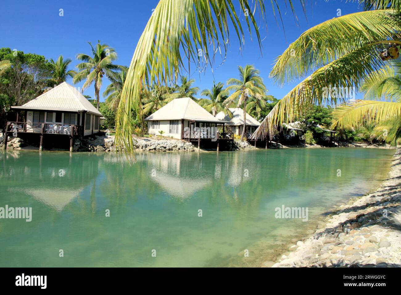 Petites cabanes le long du canal de l'île avec des palmiers Banque D'Images