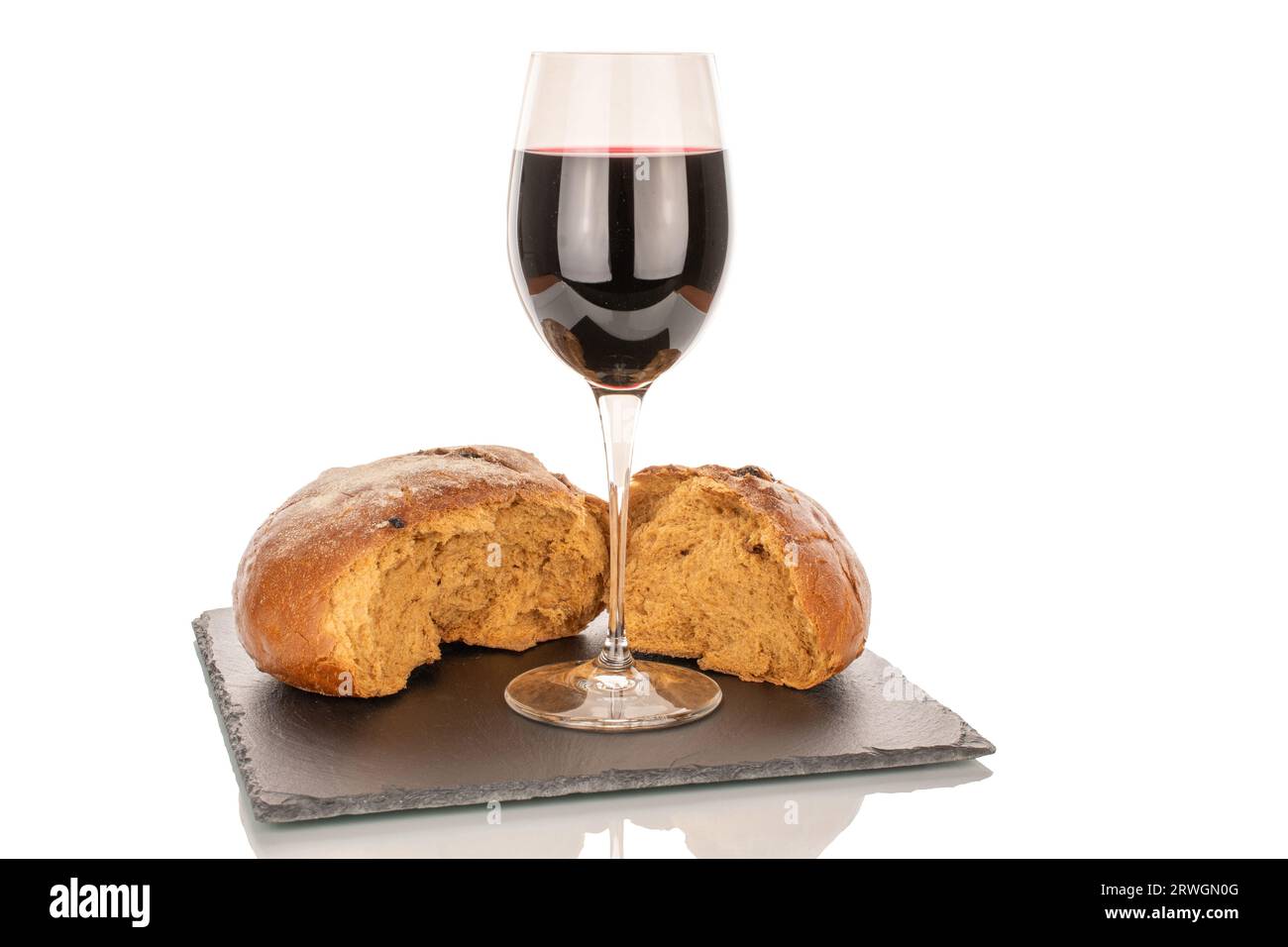 Un verre de vin rouge et deux moitiés d'une miche de pain sur un plateau d'ardoise, macro, isolé sur fond blanc. Banque D'Images