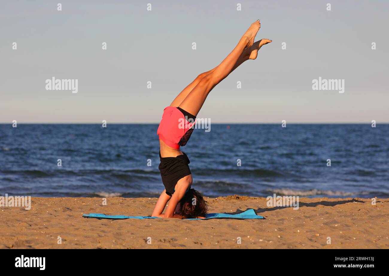 jeune fille athlétique maigre à l'envers sur la plage au bord de la mer Banque D'Images