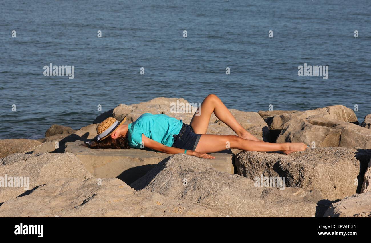 jeune fille modèle sur le rocher au bord de la mer en été Banque D'Images