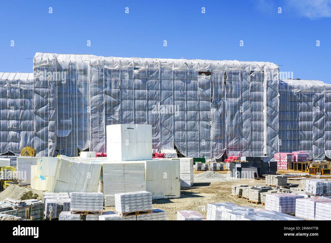 Divers matériaux d'isolation thermique dans une maison résidentielle en rénovation, dont la façade est recouverte d'un filet de protection blanc Banque D'Images