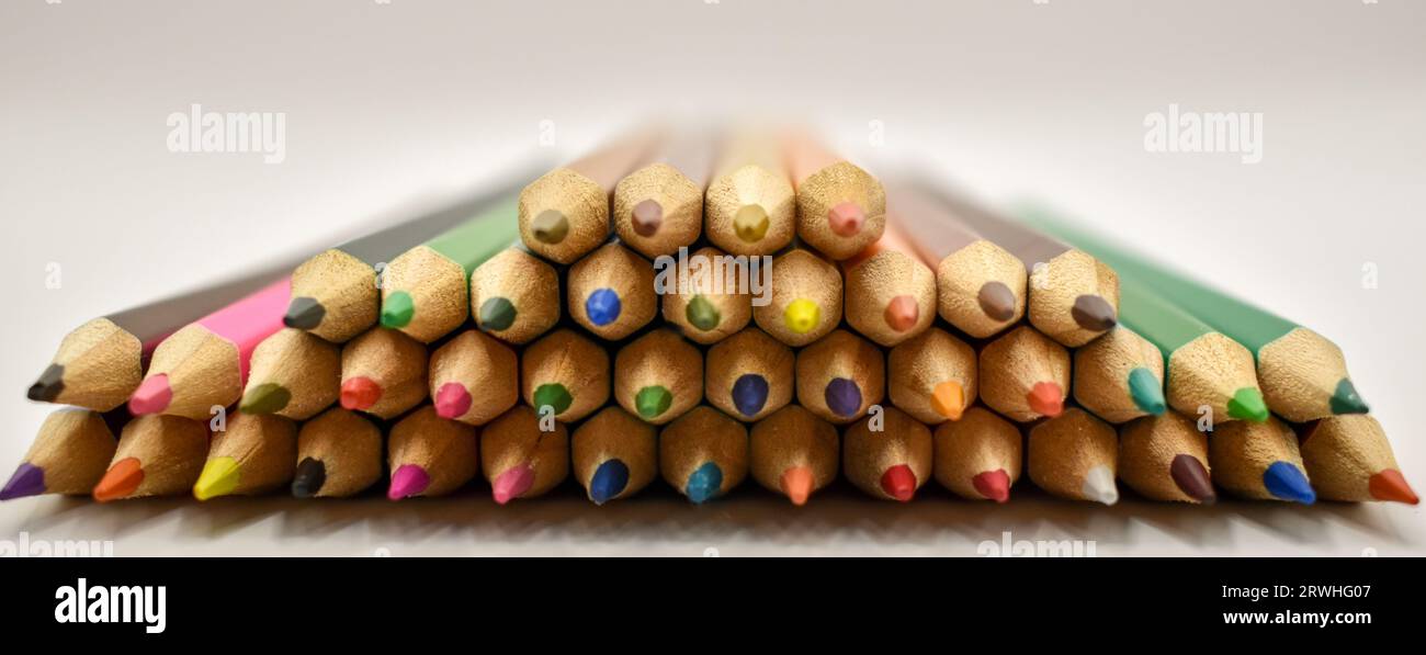 Une sélection de crayons de couleur soigneusement placés en formation sur une surface blanche sous éclairage studio. Banque D'Images