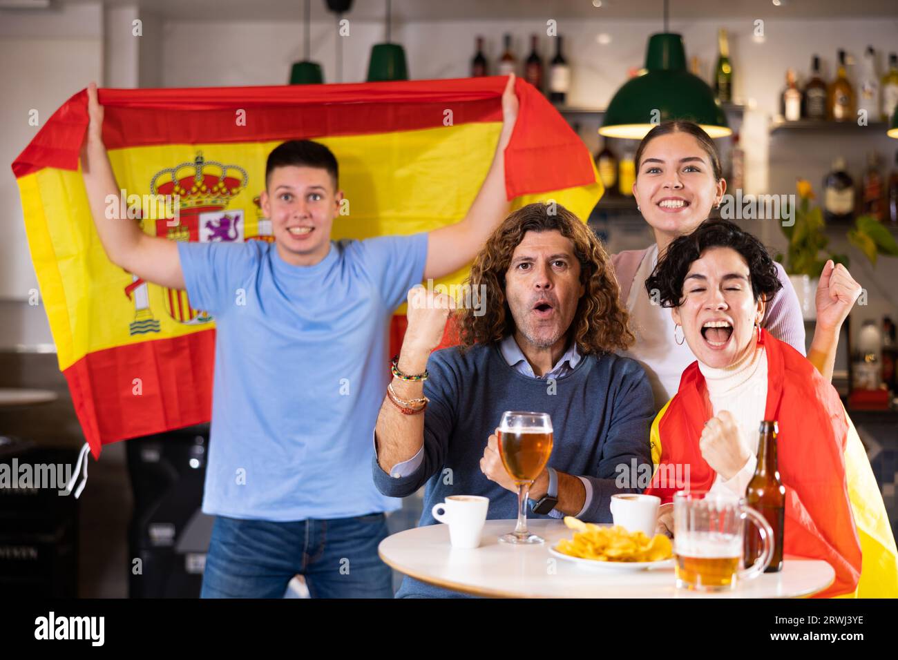 Groupe de supporters sportifs qui applaudissent à l'équipe favorite avec drapeau de l'Espagne tout en regardant le match à la télévision au bar Banque D'Images