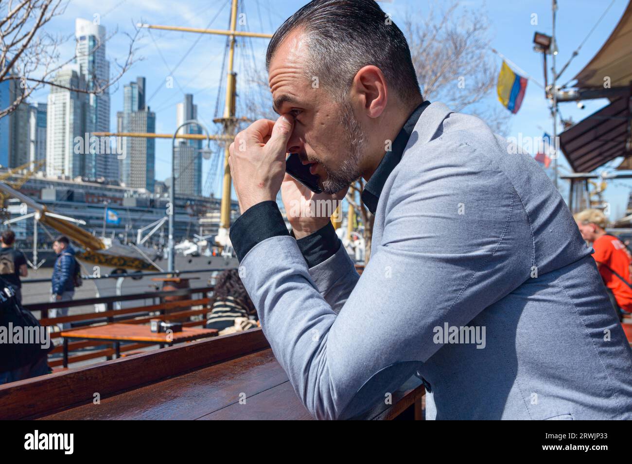 Homme d'affaires caucasien adulte en costume élégant, inquiet assis à l'extérieur du restaurant à midi en utilisant le téléphone et en pensant. Banque D'Images