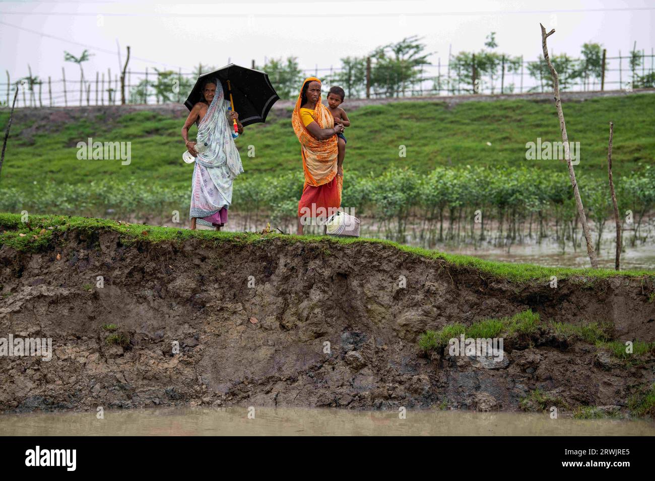 Khulna, Bangladesh. 25 août 2023. Femmes vues debout sur la rive cassée de la rivière Shibsha à Dakop Upazilla, Khulna. Il n'y a pas si longtemps, Kalabogi, un village côtier du Bangladesh, était plein de terres cultivables jusqu'à ce que la montée du niveau de la mer commence à envahir la région jusqu'au golfe du Bengale. De fréquents cyclones et inondations frappent le village depuis la fin des années 1990 En 2009, un cyclone majeur nommé Aila a détruit les 1 400 kilomètres de remblais du pays, 8 800 kilomètres de routes et environ 3 50 000 acres de terres agricoles. Plusieurs centaines de personnes auraient été tuées dans la catastrophe. Le Banque D'Images