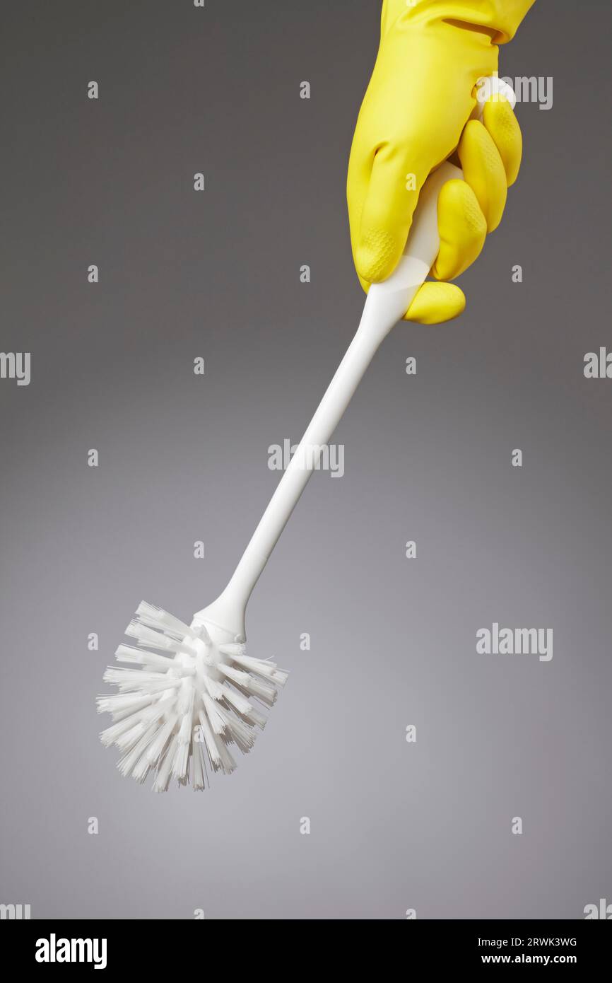 Des toilettes propres détenues par une brosse à main gant de caoutchouc jaune Banque D'Images