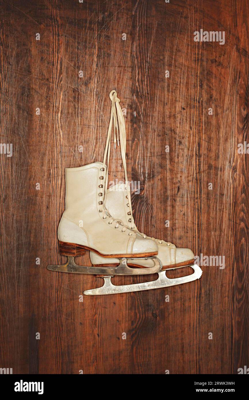 Une paire de vieux patins de femmes âgées accrochés à un mur en bois. Photographié avec un flash annulaire Banque D'Images