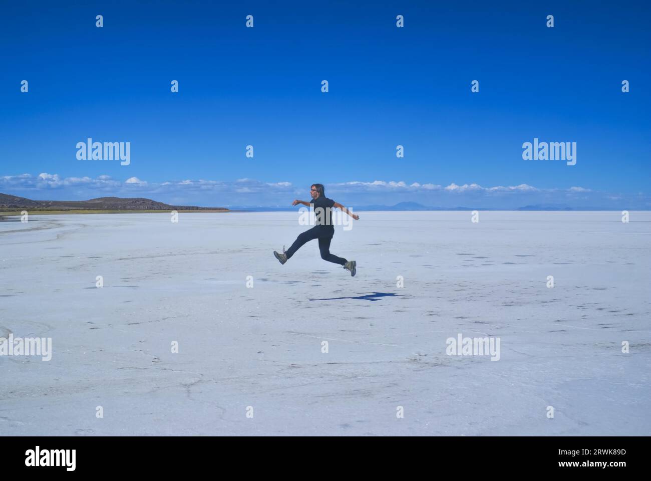 Jeune homme saute sur le vaste plan salin Salar de Uyuni en Bolivie Banque D'Images