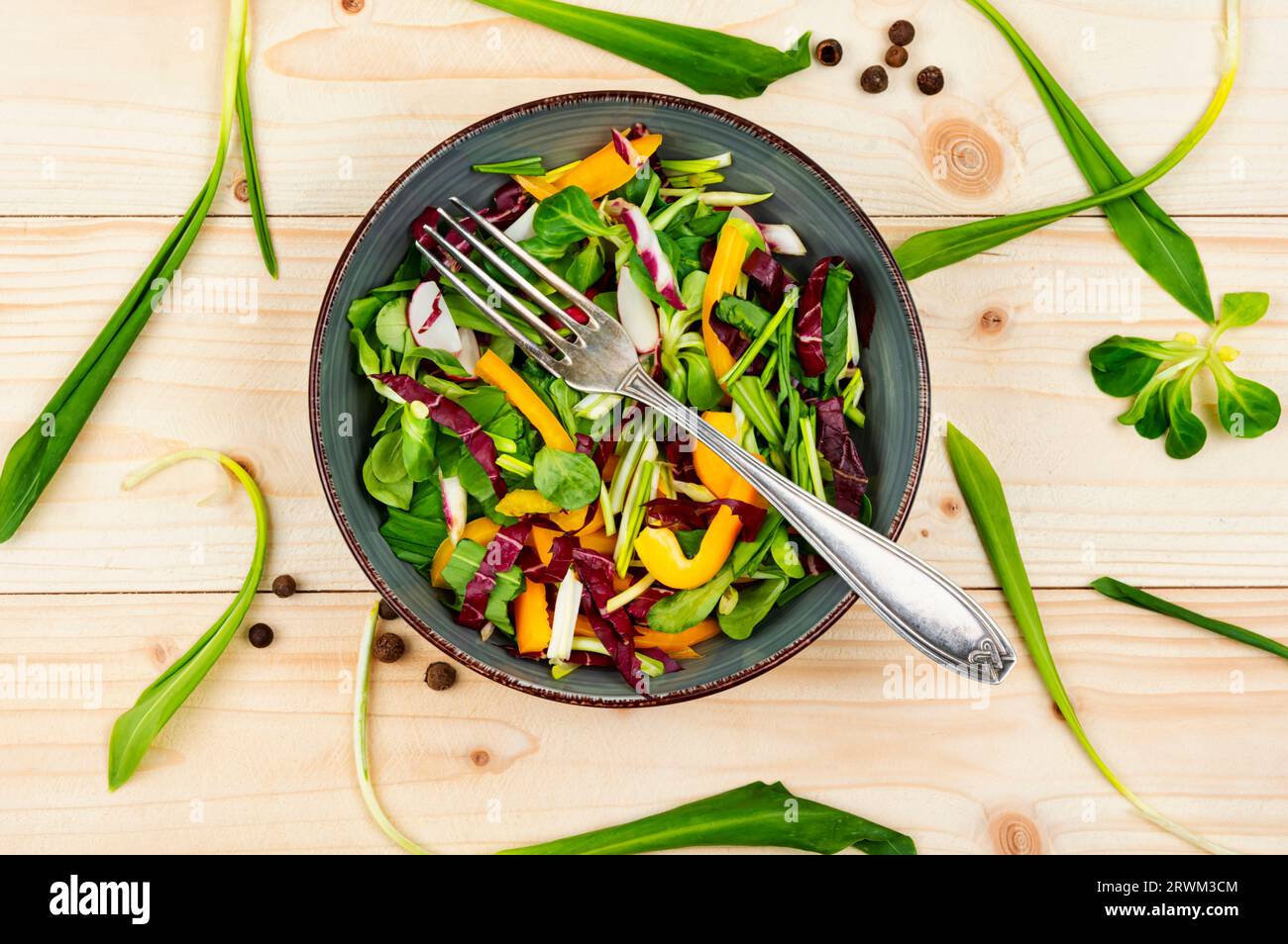 Salade saine avec des légumes et des feuilles d'ail sauvage sur une planche de bois rustique. Banque D'Images