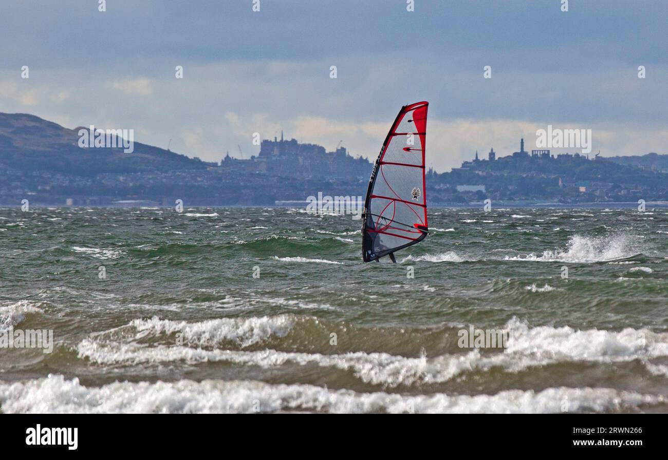 Longniddry, East Lothian, Écosse. 20 septembre 2023. Le temps de l'après-midi est bon pour la paire de windsurfeurs expérimentés à The Bents. Marée basse à East Lothian avec la ville d'Édimbourg en arrière-plan. Vent de 28 km/h rafales potentielles de 45 km/h avec un Firth of Forth saccadé. Banque D'Images