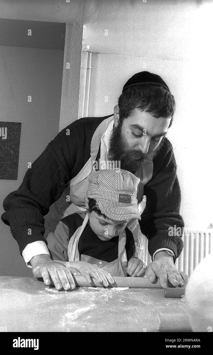 Des enfants juifs des Congrégations hébraïques de Birmingham et Solihull ont participé à une boulangerie matzo pré-PÂQUE en mars 1991 au Centre Lubavitch à Willows Road Birmingham. Enseignant aux enfants les règles de cuisson du pain sans levain sont Rabbi Herschel Rader, ministre de la synagogue de Solihull et le professeur Sam Aburdaram, directeur de l'école de cheder de Solihull ; Rabbi Rader montre Yuddi Gershon âgé de quatre ans comment rouler la pâte de Pâque pour les matzos. Banque D'Images