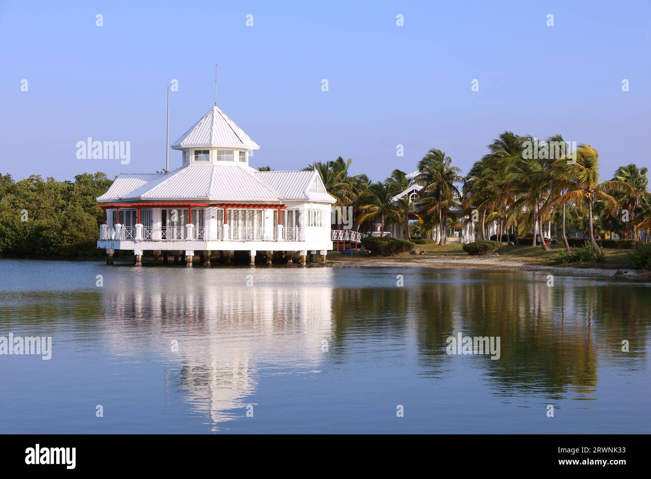 Vue pittoresque à la maison blanche sur pilotis sur la plage de la mer tropicale avec des palmiers de cocotiers. Villa dans une baie sur l'île des Caraïbes Banque D'Images