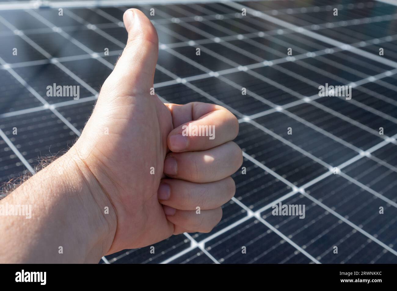 Geste main dans le pouce vers le haut sur l'arrière-plan flou propre des panneaux solaires Banque D'Images