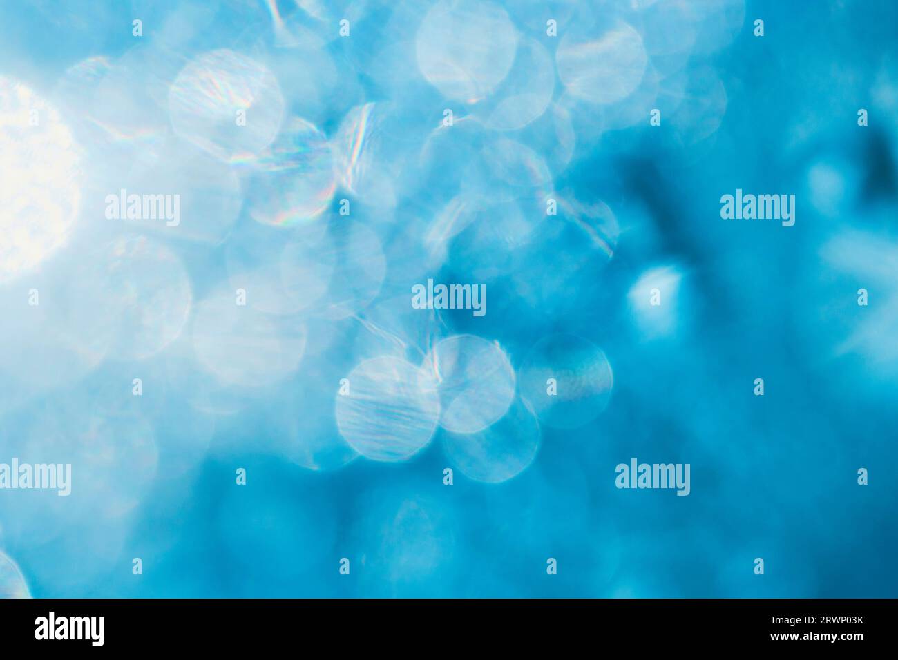 Fond bleu abstrait avec bokeh rond de gouttes de pluie sur verre éclairé par la lumière du soleil Banque D'Images